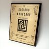 Aukso atspalvio įmonės jubiliejaus plaketė su geometriniu apvadu.
