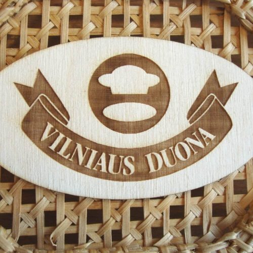 Medinis ovalus ženklelis su graviruotu „Vilniaus duona“ logotipu prie pintinės