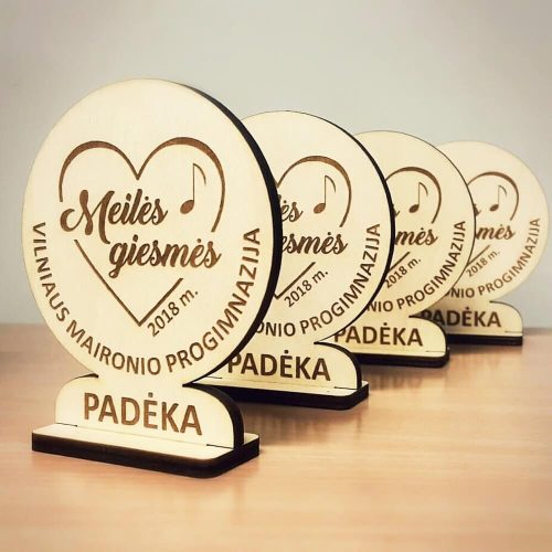 Apvalios medinės padėkos statulėlės su širdies ir natos piešiniu ant stovelių.