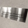 Nerūdijančio plieno iškaba su priešgaisrinės apsaugos departamento pavadinimu.