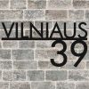 Juodas išpjautas užrašas „Vilniaus 39“ ant plytų sienos.