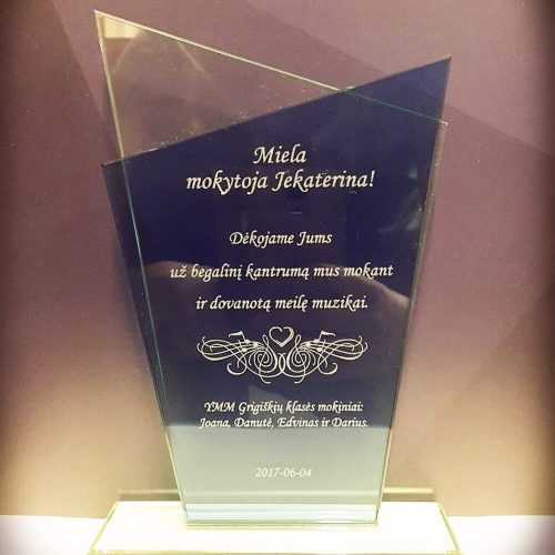 Aukšta stiklinė padėka muzikos mokytojai su natų ornamentu.