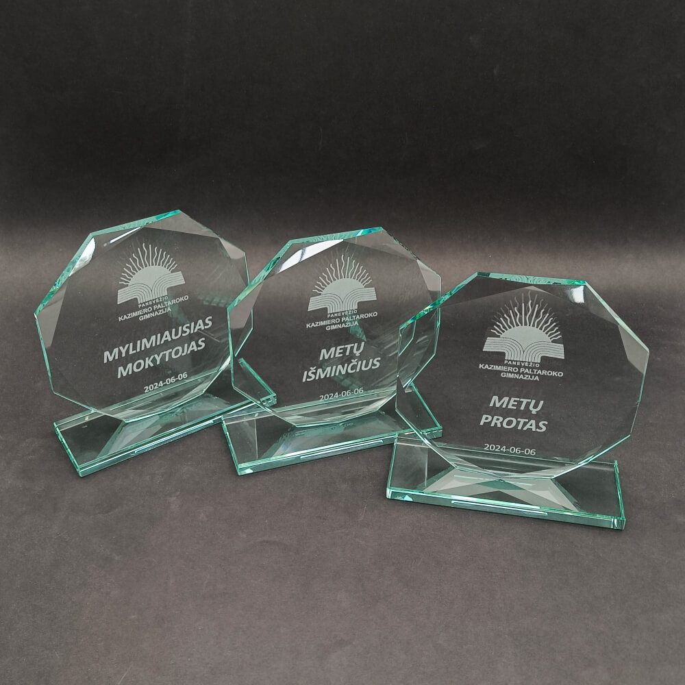 Trys daugiakampiai stikliniai mokyklos apdovanojimai su mokytojų ir metų nominacijomis.