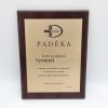 Padėkos plaketė gydytojui Vytautui ant tamsaus medinio pagrindo.