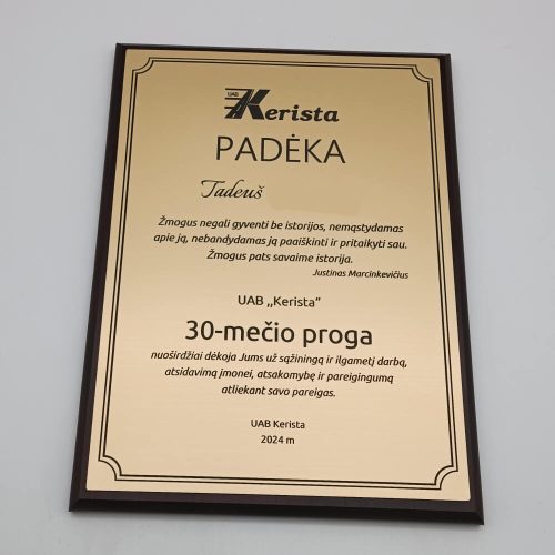 Aukso atspalvio padėkos plaketė už ilgametį darbą tamsiame rėmelyje.