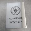 Nerūdijančio plieno lentelė su advokatų kontoros pavadinimu ir emblema.