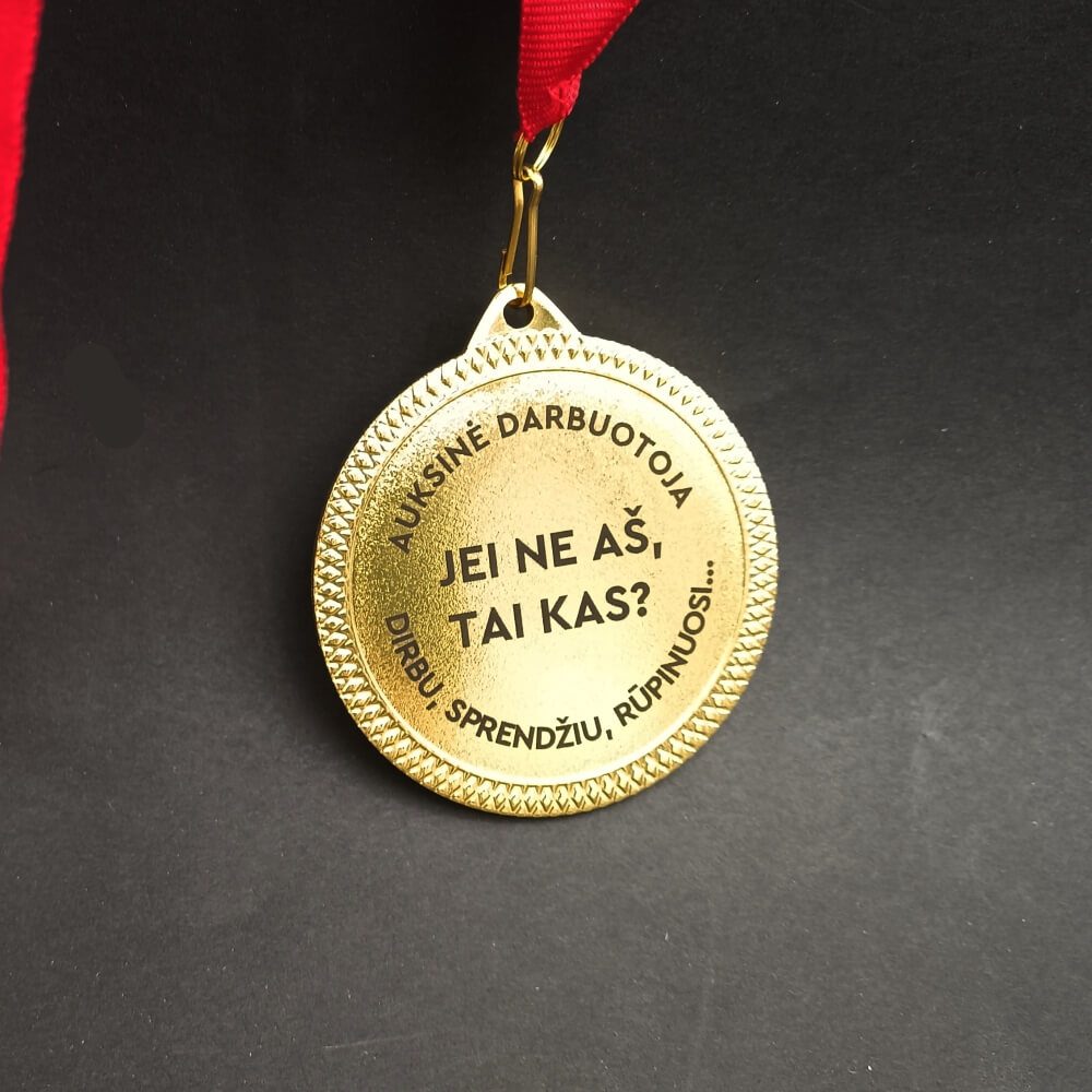 Aukso spalvos apvalus medalis su raudona juostele ir nominacija „Auksinė darbuotoja“.
