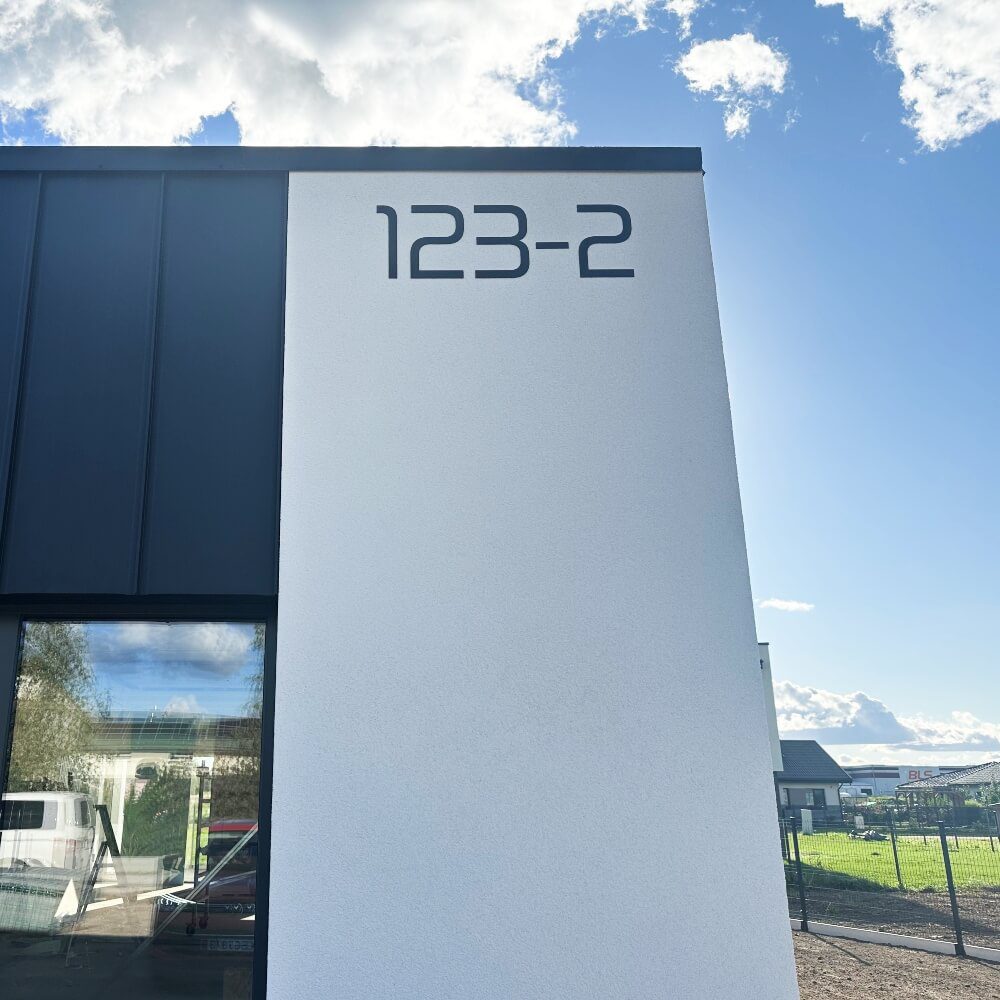 Namo numeris 123-2 viršutinėje kiemo vartų stulpo dalyje.