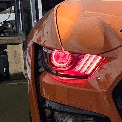 „Cobra“ simbolis apskritoje „Ford Mustang“ žibinto dalyje, apšviestoje raudona šviesa