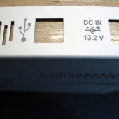 Metalinis elektronikos prietaiso skydelis su pažymėtais USB ir maitinimo simboliais