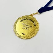 Aukso atspalvio apvalus „Camino de Santiago“ medalis su graviruotu įveiktu atstumu.