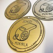 Trys apvalūs mokyklos medaliai su švilpuko piešiniu, aukso ir sidabro atspalvių.