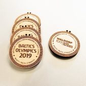 Šviesaus medžio apvalūs „Baltics Olympics 2019“ medaliai su graviruotu ornamentu.