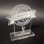 Skaidraus organinio stiklo „Food Safety Award“ apdovanojimas ant pagrindo.