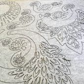 Lazeriu išpjauti dekoratyviniai ornamentai pilkame sintetiniame veltinyje.